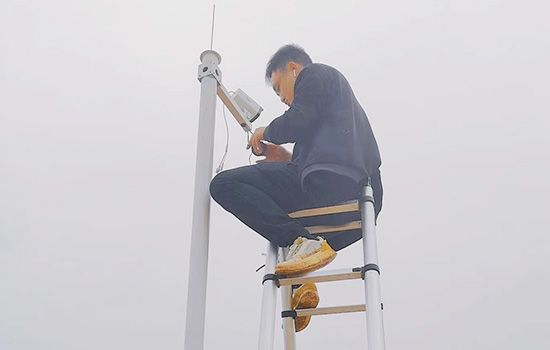 A man straddling a double telescopic ladder checking a camera