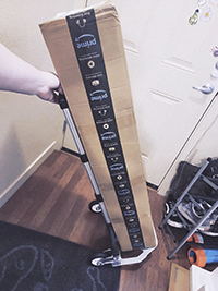 A long carton is being placed on a  collapsible dolly