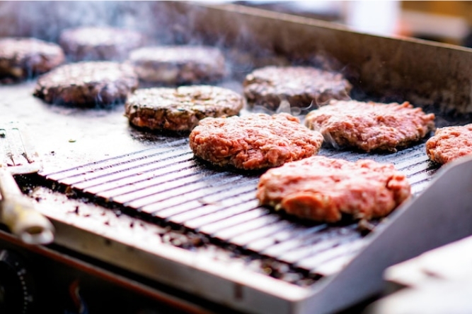Searing burger patties with even crusts on a flat-pan griddle