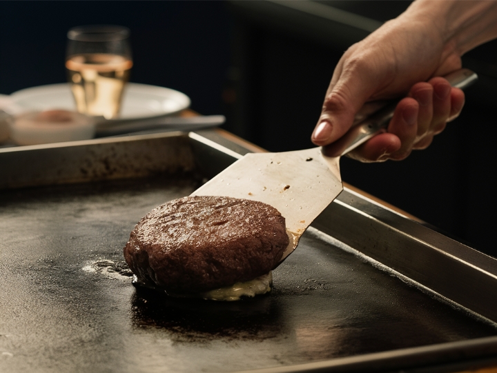 Flipping a burger patty with a wide metal spatula