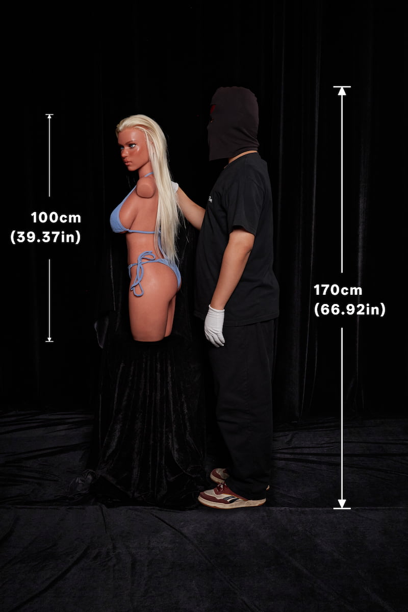 ULW 883# Fiora: This side-profile comparison shot features the blonde doll in a blue bikini standing next to an adult male, highlighting its voluminous firm bust and rounded buttocks profile, with healthy skin naturally textured by subtle freckles.