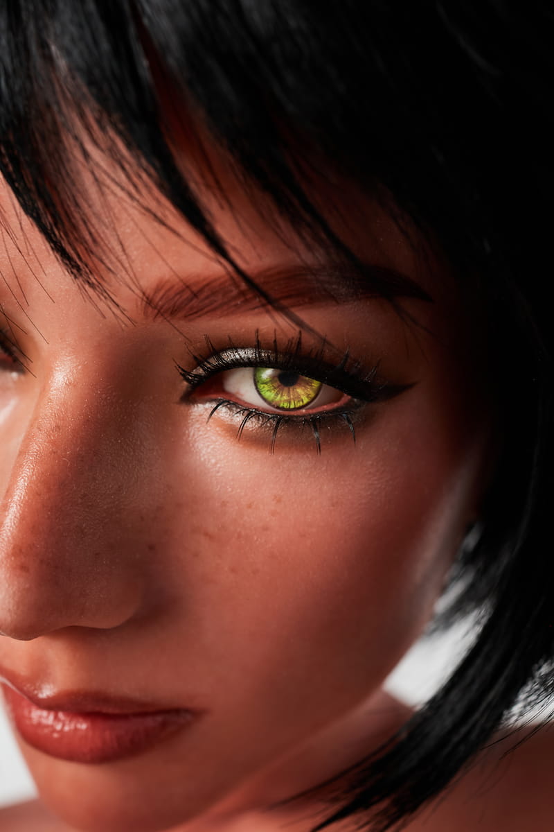 ULW 882# Livia: This eye close-up features deep, striking green eyes with exquisite makeup; the fair skin is detailed with natural freckles, while thick lashes and sharp eyeliner create a captivating and realistic gaze.