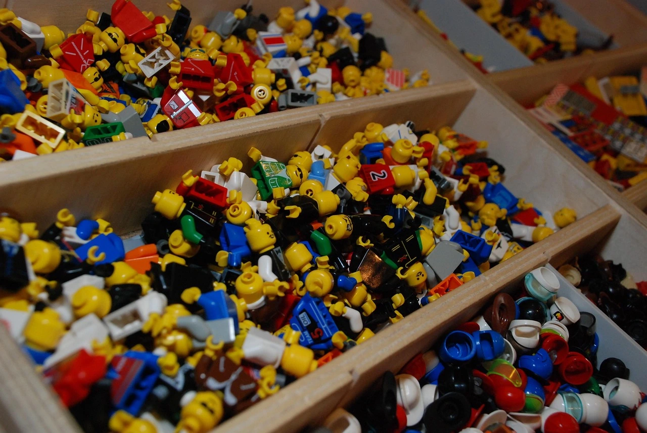 Minifigures with different expressions and body parts are scattered in the box