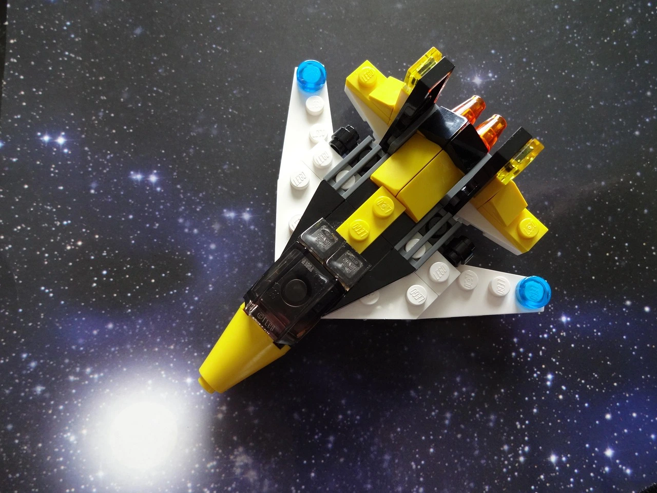 A small airplane made of different MOC building blocks has a background of a vast expanse of space, as if it were soaring through the universe.