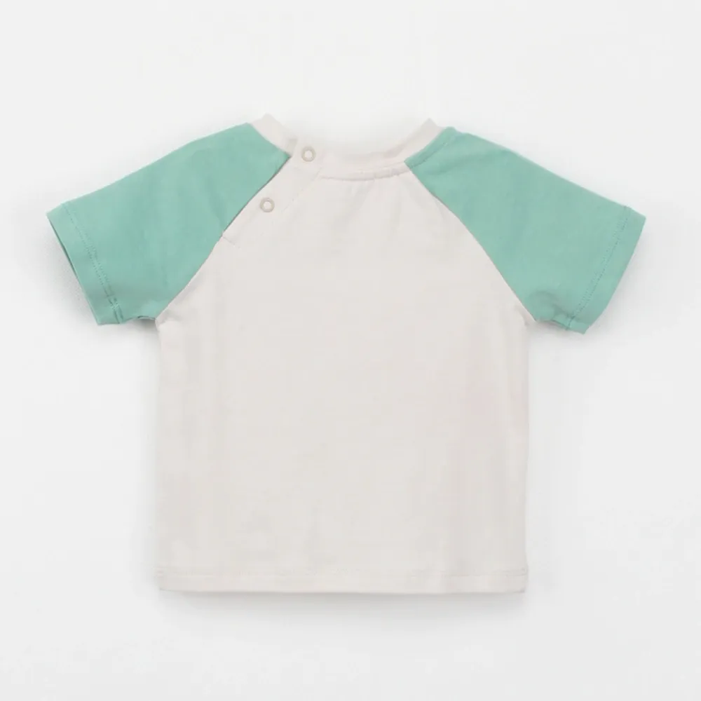 Back view of SENSENG unisex baby Leo raglan short sleeve tee in plant-dyed botanical natural powder puff and green colorway, showing the sporty contrast shoulder layout
