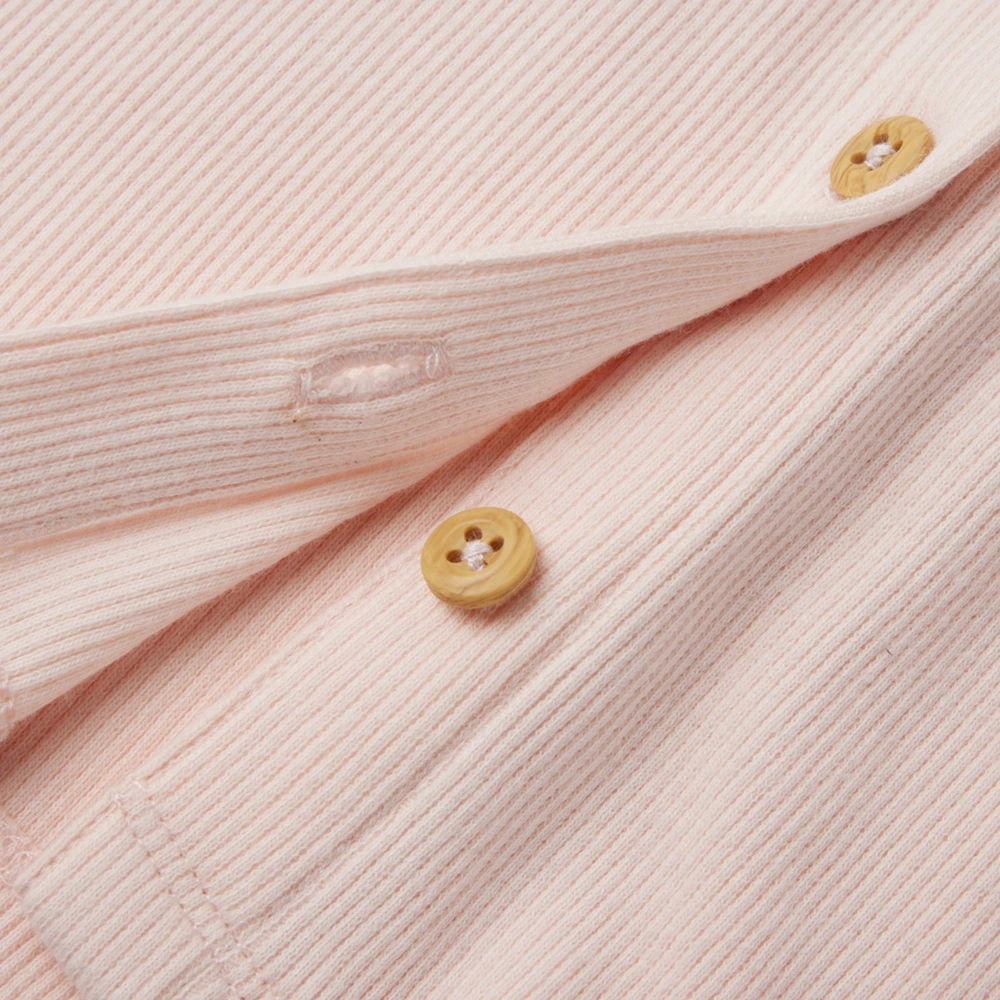 close up of front on girl long sleeve ribbed button-up top and pants set made from organic cotton with natural plant dyes