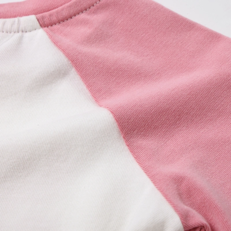 Close-up of the seamless color-block integration between the natural white body and the strawberry pink organic cotton raglan sleeve.