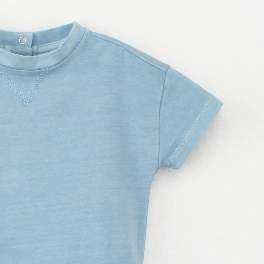 Close-up view of the neckline details of the bonnie blue Arthur plant-dyed organic cotton drop shoulder bubble bodysuit, featuring the snap fastener opening and V-stitching detail.