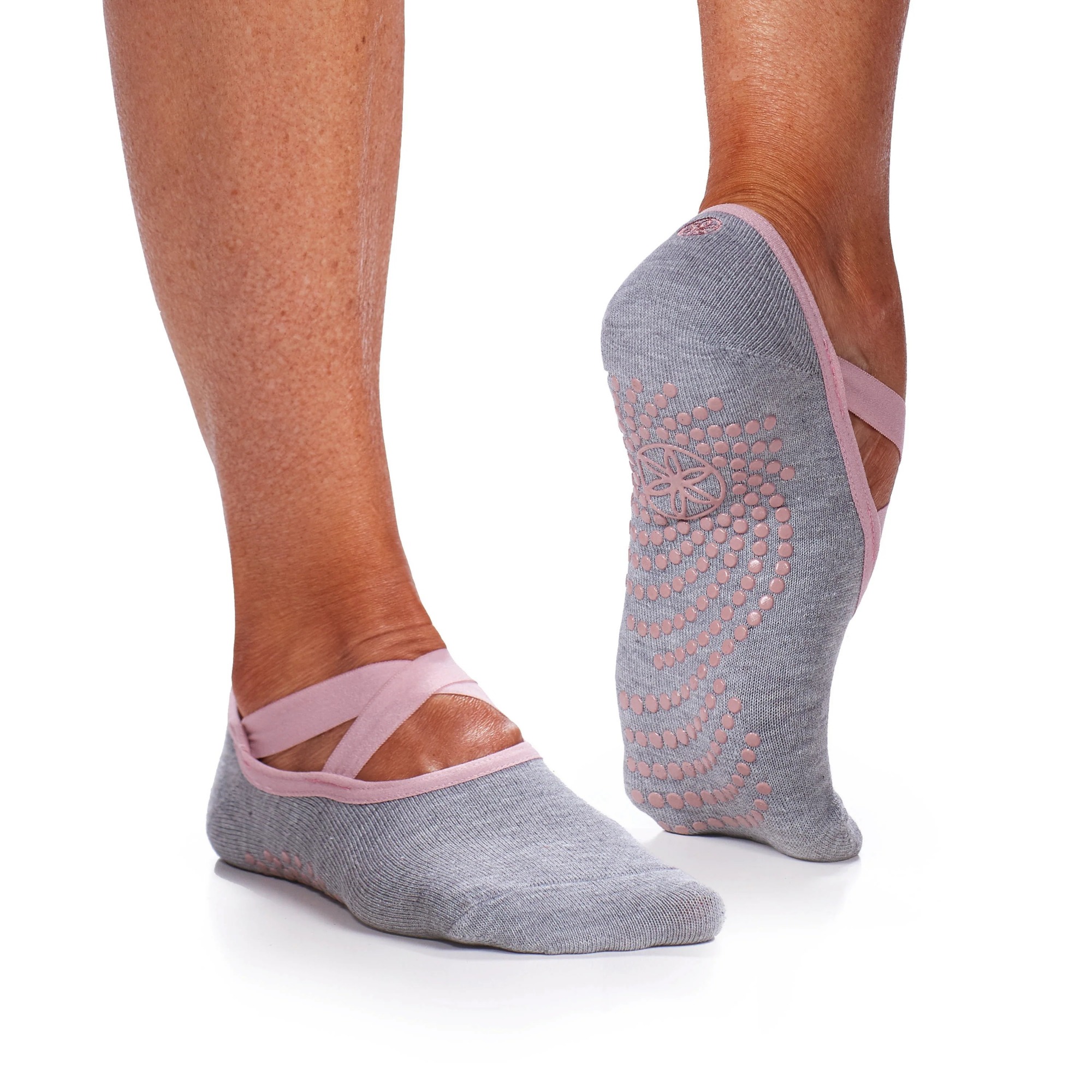 Ballet-style grip socks contacting flat indoor floor during toe-raised balance position