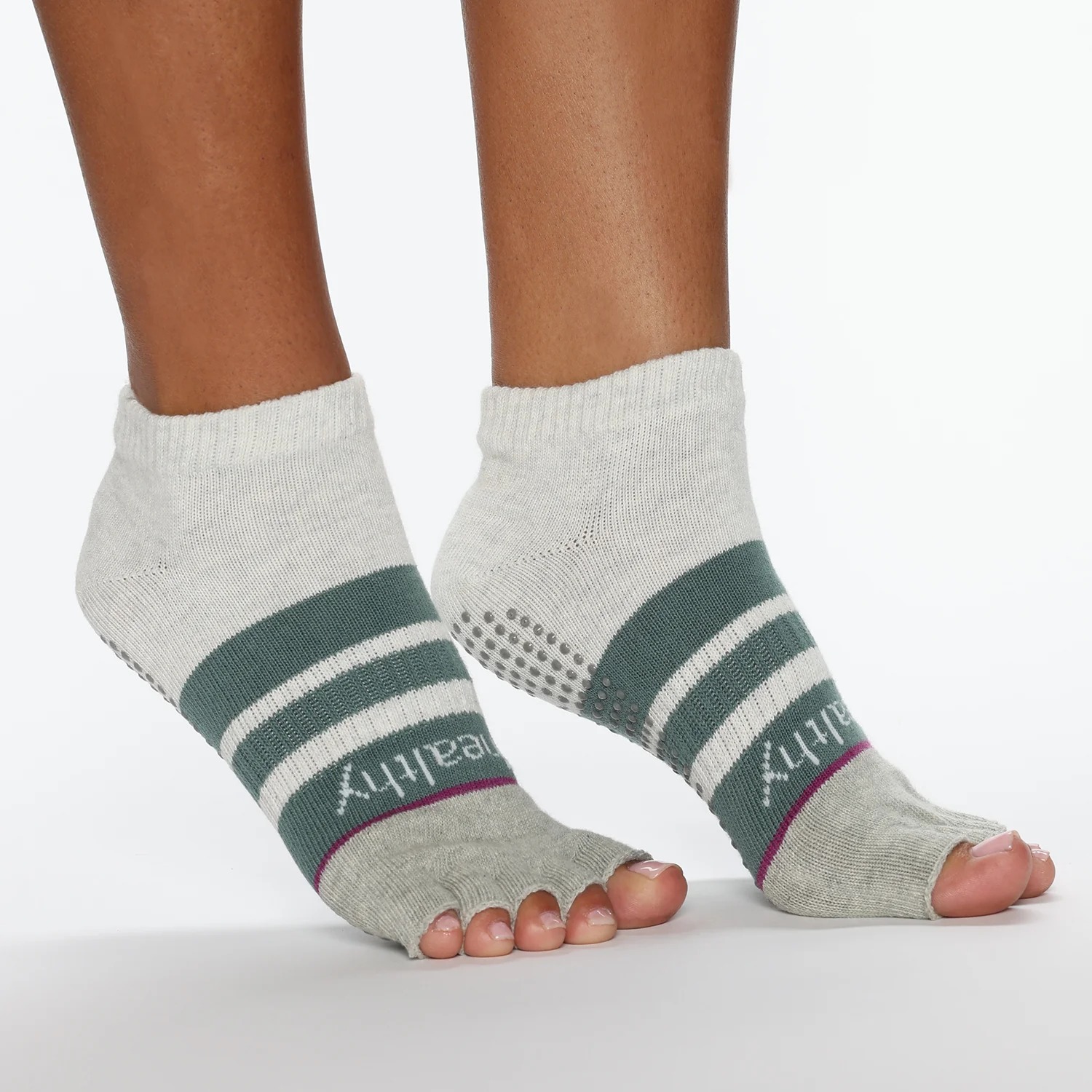 Open-toe grip socks showing forefoot and toe contact during light balance stance on smooth indoor floor