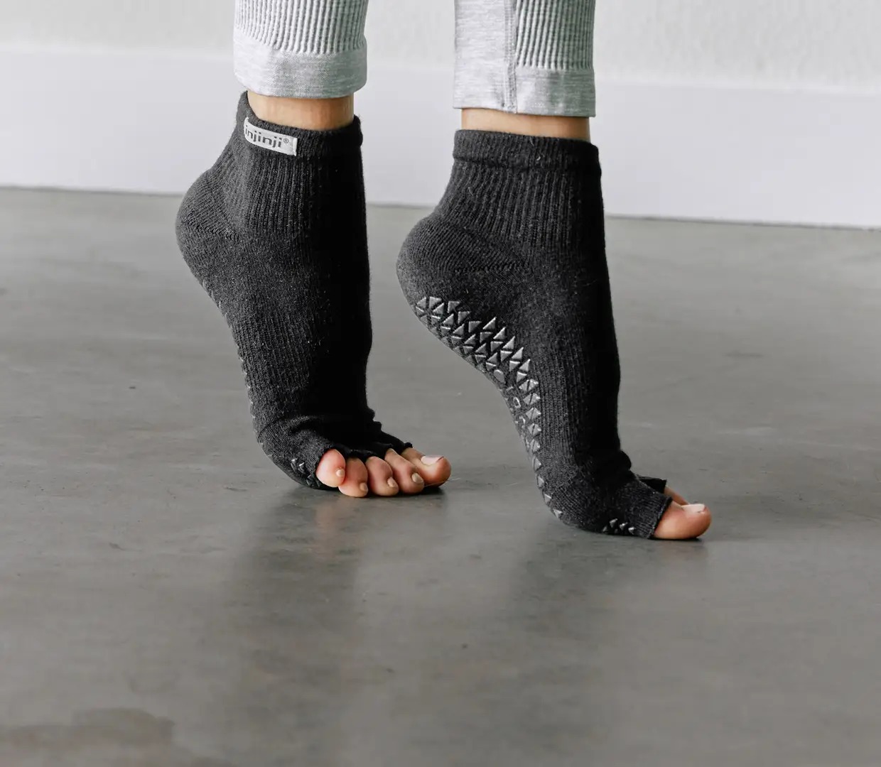 Feet wearing grip socks contacting smooth indoor concrete floor during upright stance
