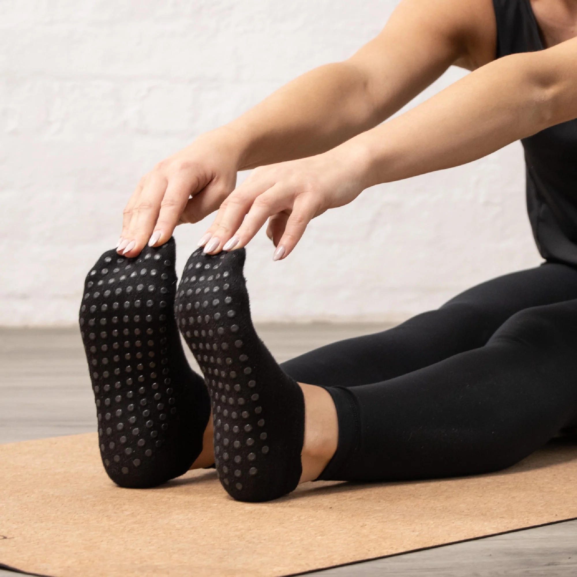 Feet wearing grip socks contacting yoga mat during seated forward stretch