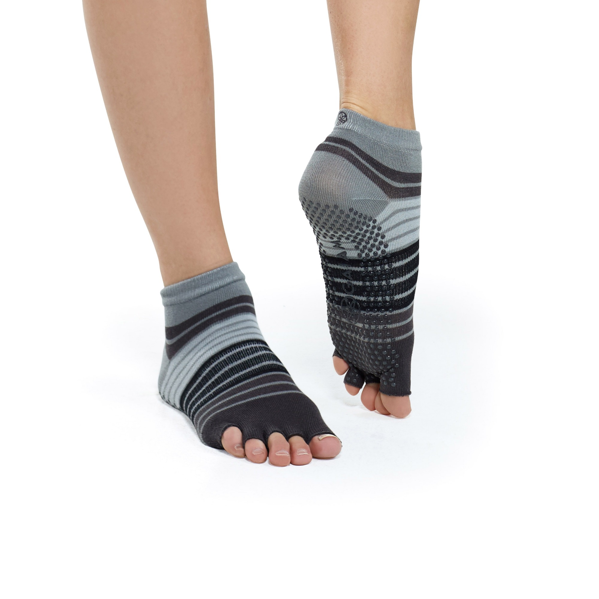 Feet wearing toeless grip socks contacting flat indoor floor surface during upright stance