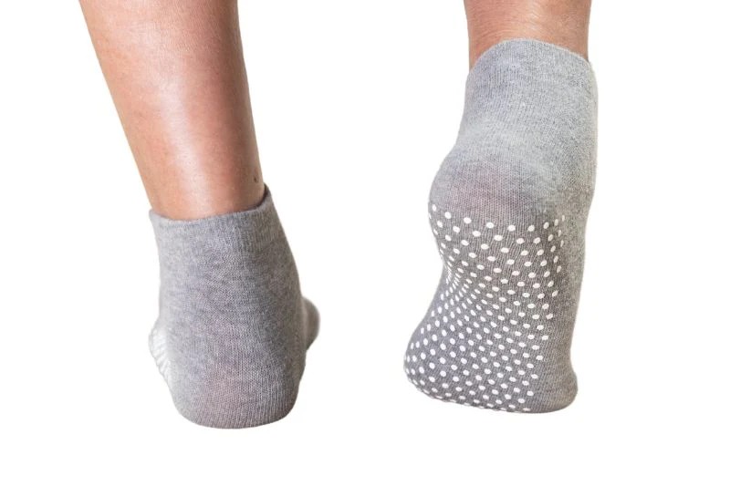 Grey non-slip grip socks showing silicone dot traction pattern on heel and forefoot for indoor floor stability