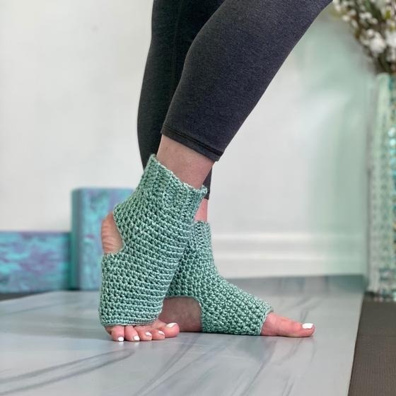 Feet wearing open‑toe knit socks contacting smooth indoor floor during seated stretch pose
