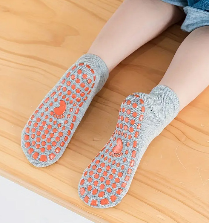 Grip socks worn indoors showing full-sole silicone grip dots on a wooden surface