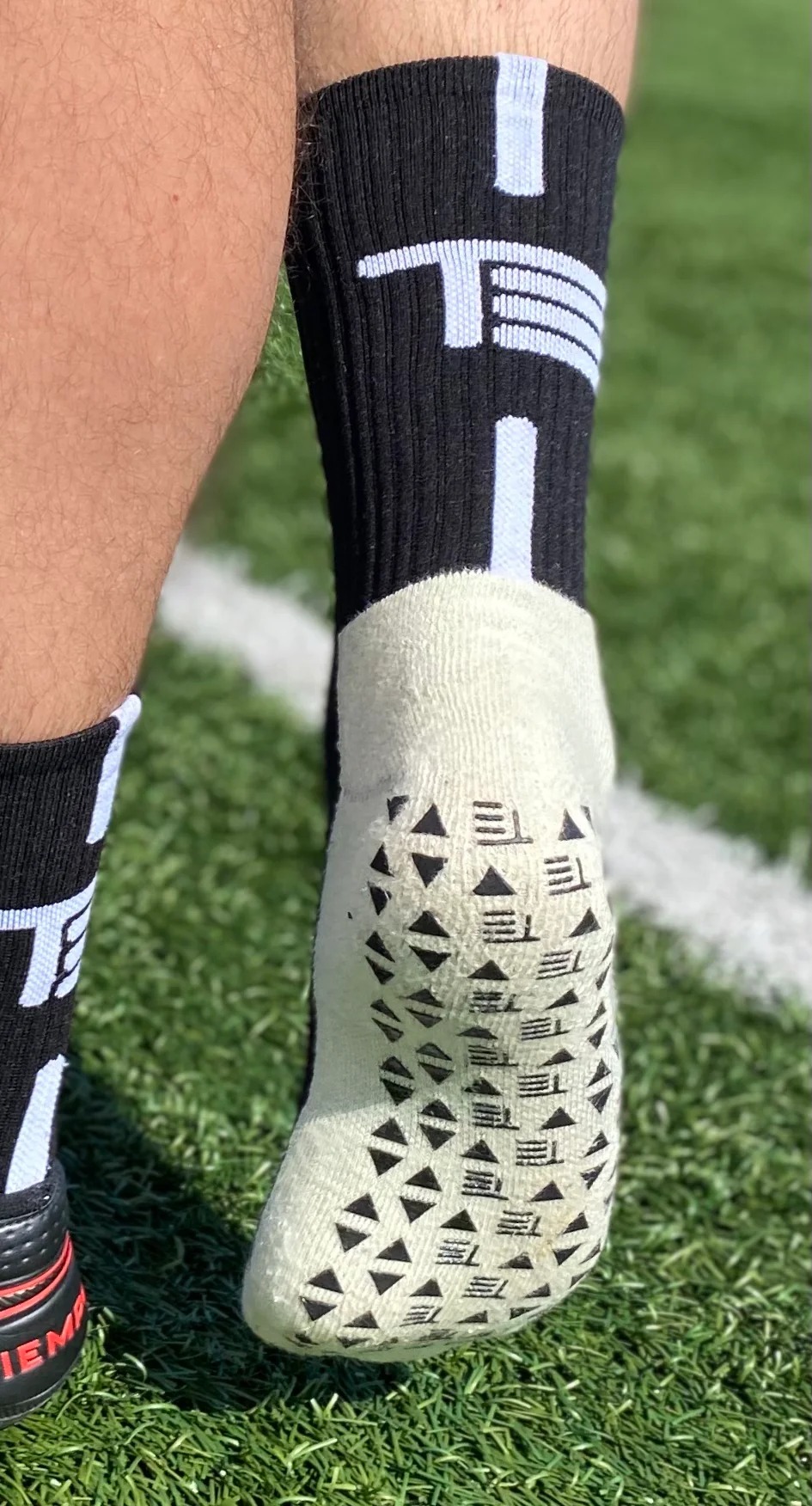 Non-slip grip socks with triangular traction elements during movement, illustrating friction contact behavior on hard, smooth tile-like surfaces