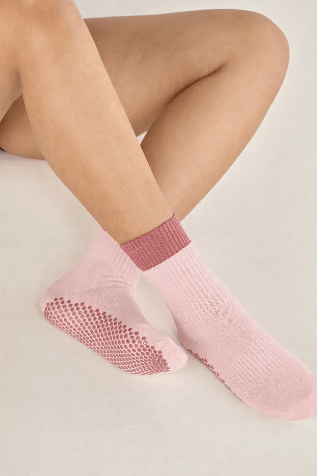 Light pink ankle yoga grip socks with dense non-slip dots on sole, minimalist background, comfortable studio wear focus