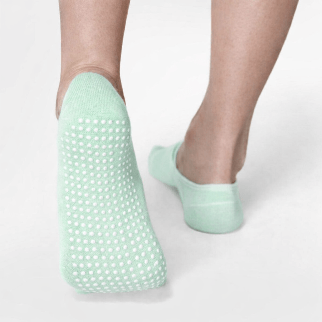 Mint green yoga grip socks with white anti-slip dots on sole, low-cut design, clean studio background, close-up foot detail
