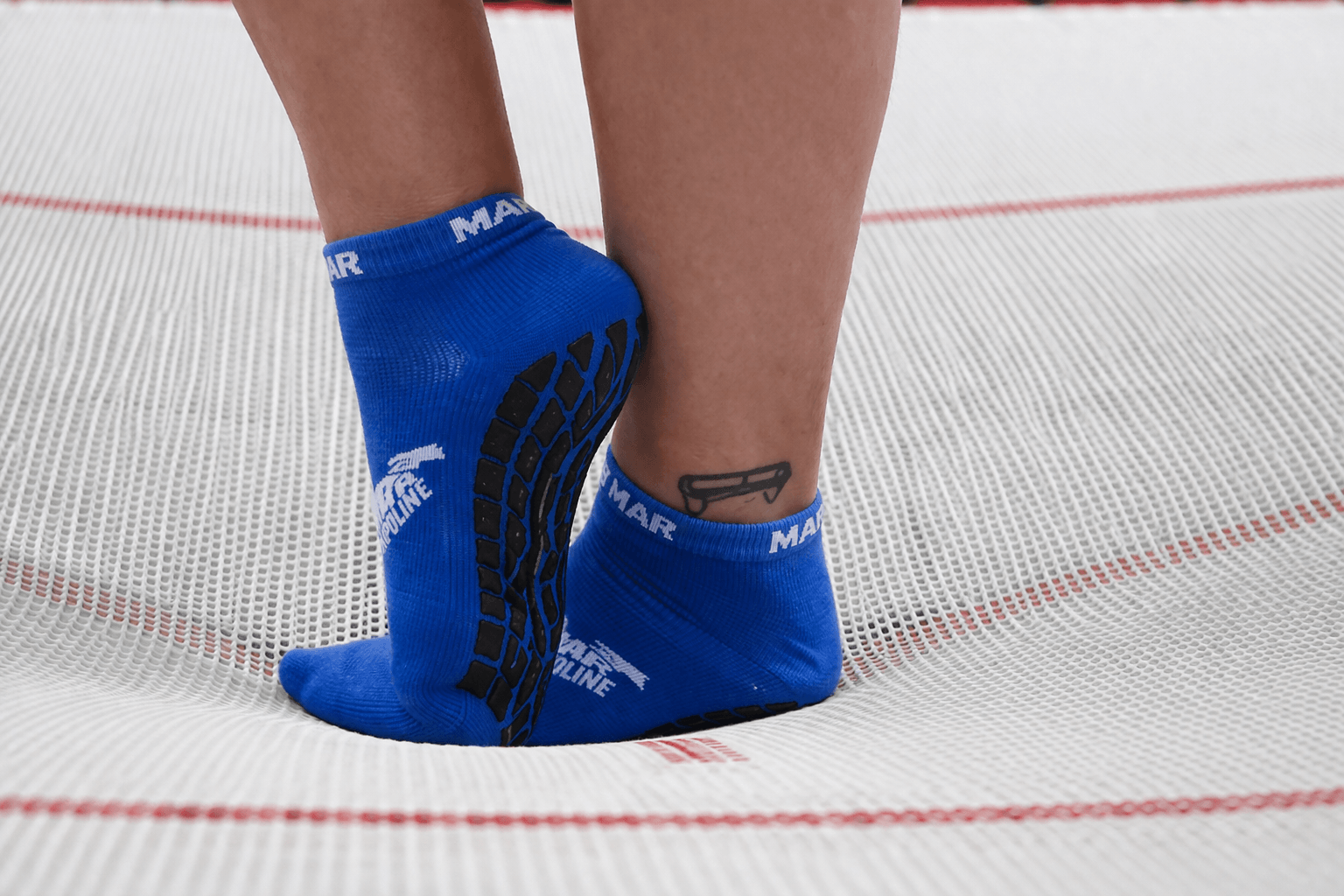 blue grip socks for trampoline parks on trampoline surface, professional trampoline park socks supplier, jump socks bulk safety socks