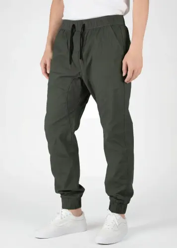  Front view detail of ItalyMorn men's army green jogger pants on a model, highlighting the elastic waistband with black drawstrings, deep side pockets, and slim-tapered fit