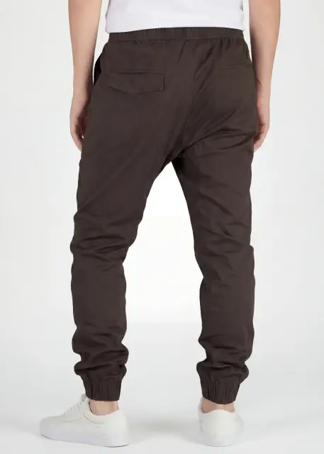 Back view of ItalyMorn men's coffee brown jogger pants on a model, highlighting the secure back pockets, well-fitted seat, and comfortable ribbed ankle cuffs.
