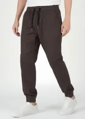 Angled front view of ItalyMorn men's coffee brown jogger pants mid-step, emphasizing the smooth drape of the premium fabric, reinforced side seams, and flexible everyday fit