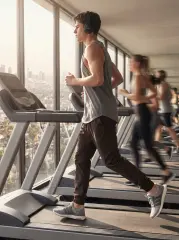  A man running on a treadmill in a high-rise gym wearing ItalyMorn men's coffee brown jogger pants, illustrating the pants' high flexibility and performance for indoor fitness training
