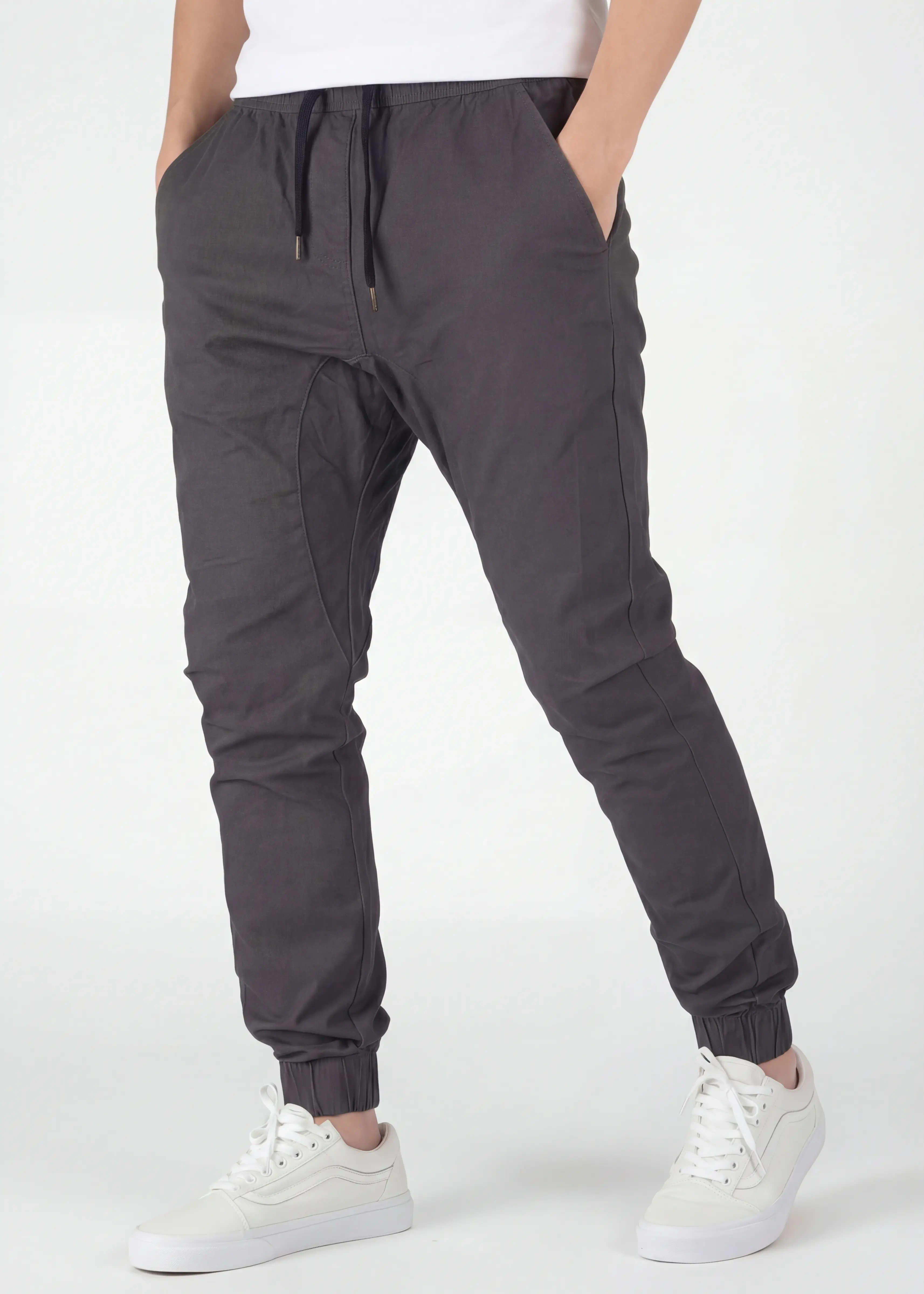 Angled front view of ItalyMorn men's olive grey jogger pants with hands in pockets, emphasizing the relaxed yet tailored fit and the smooth drape of the premium fabric