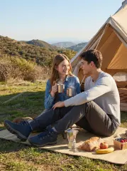 A couple enjoying coffee while sitting outside a canvas tent at a campsite; the man is wearing ItalyMorn men's dark grey jogger pants paired with hiking boots, showcasing a comfortable and rugged outdoor lifestyle outfit