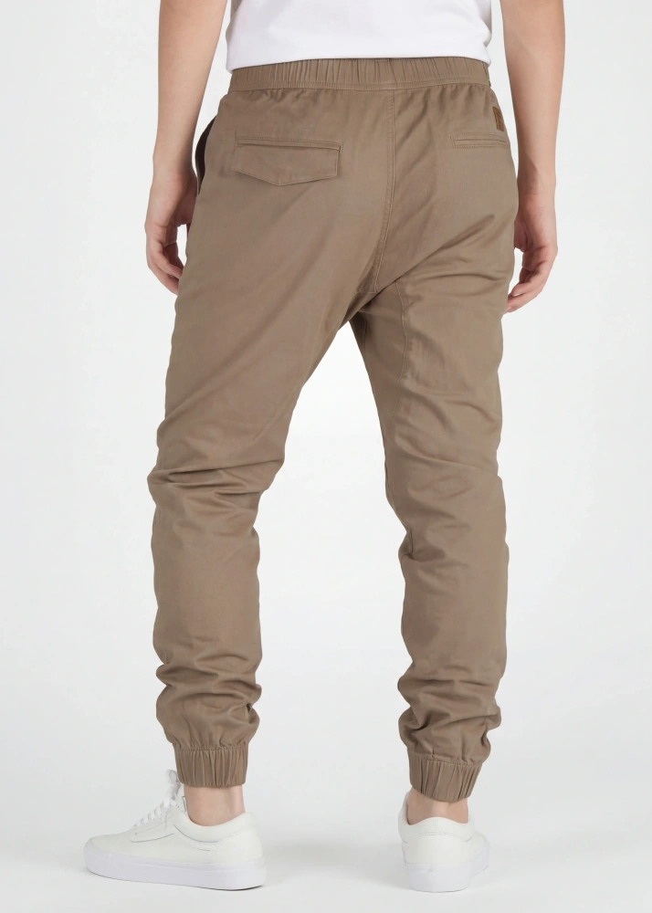A rear view close-up of ItalyMorn men's dark khaki jogger pants on a model, highlighting the functional back pockets, clean fit, and durable fabric texture. Paired with white sneakers