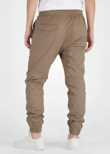 A rear view close-up of ItalyMorn men's dark khaki jogger pants on a model, highlighting the functional back pockets, clean fit, and durable fabric texture. Paired with white sneakers