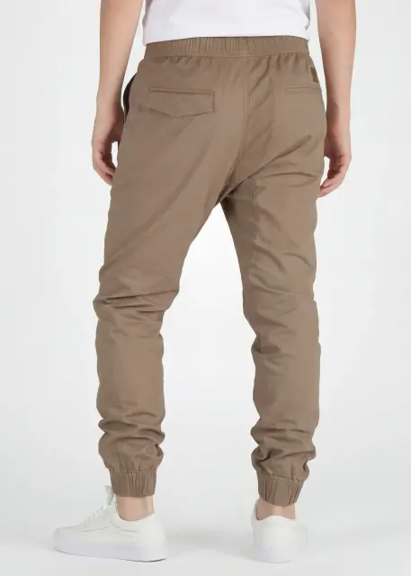 A rear view close-up of ItalyMorn men's dark khaki jogger pants on a model, highlighting the functional back pockets, clean fit, and durable fabric texture. Paired with white sneakers