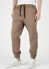 A detailed close-up view from the front of ItalyMorn men's dark khaki jogger pants, showcasing the elastic waistband with drawstrings, practical front pockets, and ribbed cuffs. A model's lower body is shown, wearing white sneakers