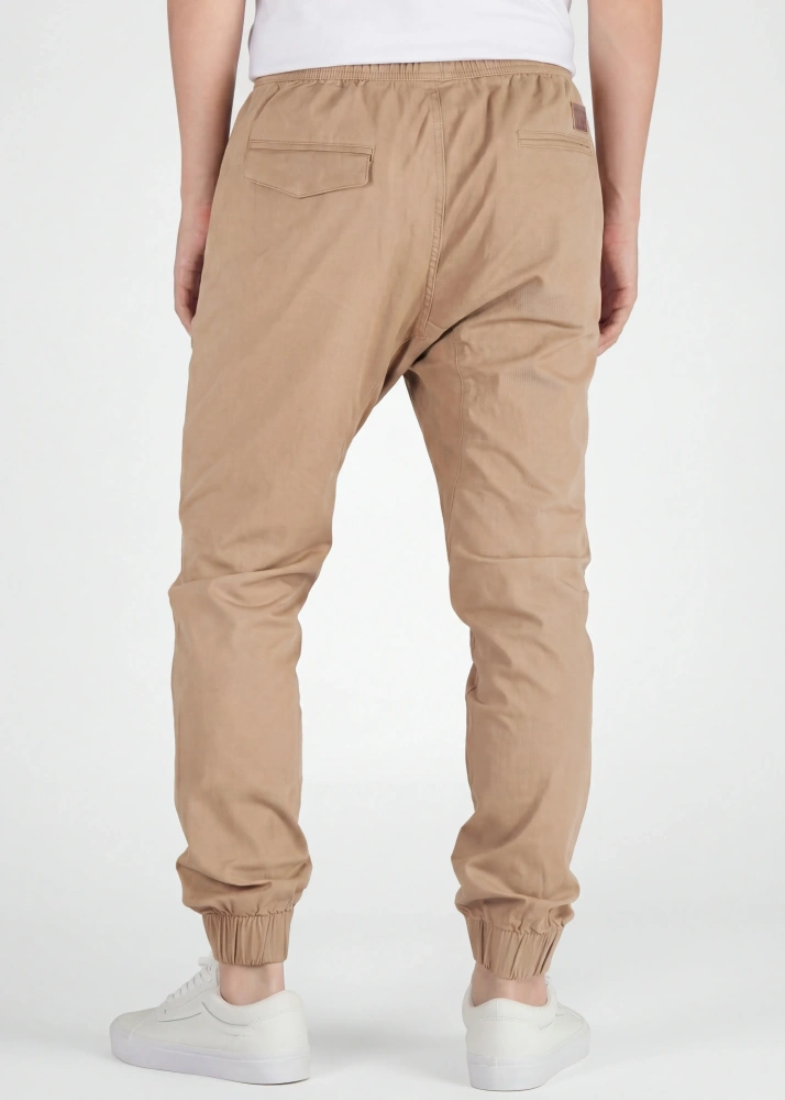 A rear view close-up of ItalyMorn men's khaki jogger pants on a model, highlighting the functional back pockets, clean fit, and durable fabric texture. Paired with white sneakers.