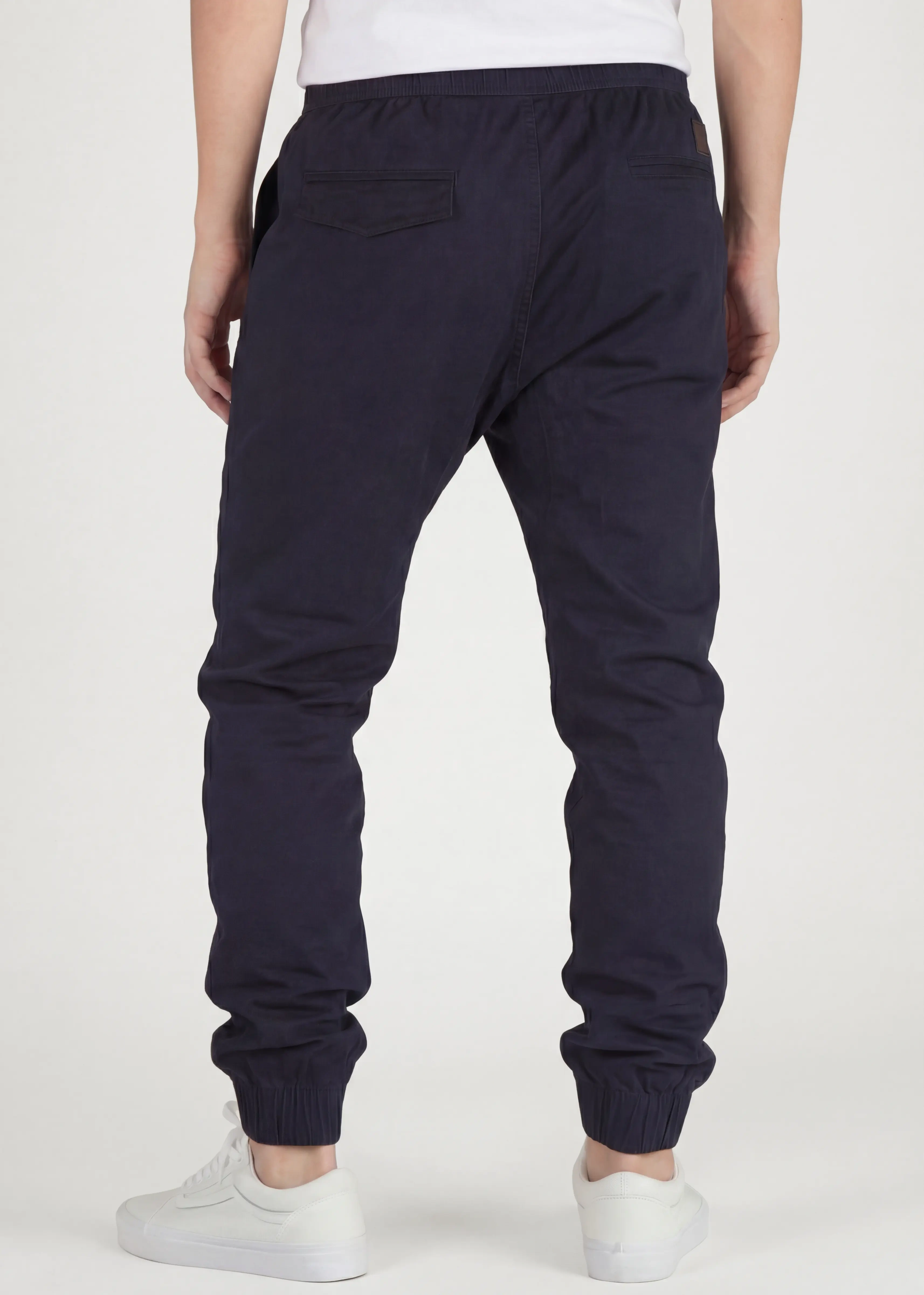  Back view of ItalyMorn men's navy blue jogger pants on a model, showing the clean tailored fit, functional back pockets, and snug ribbed ankle cuffs