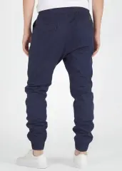 A rear close-up view of ItalyMorn men's navy blue jogger pants, showcasing the clean tailored fit, functional back pockets with flap detail, and secure ribbed ankle cuffs. Paired with white sneakers.