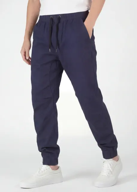 An angled front view of ItalyMorn men's navy blue jogger pants on a model with one hand in pocket. This highlights the smooth drape of the premium fabric, the reinforced side seams, and the versatile everyday fit