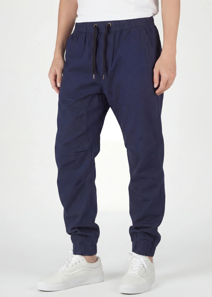  A close-up front view of ItalyMorn men's navy blue jogger pants on a model, highlighting the comfortable elastic waistband with black drawstrings, deep side pockets, and slim-tapered silhouette. Paired with white sneakers