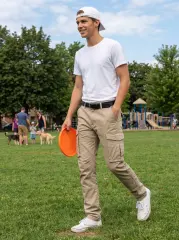 A young man smiling and walking in a sunny park with a frisbee, wearing a white t-shirt and ItalyMorn men's khaki cargo pants, showcasing a relaxed and comfortable outfit for active weekend leisure.
