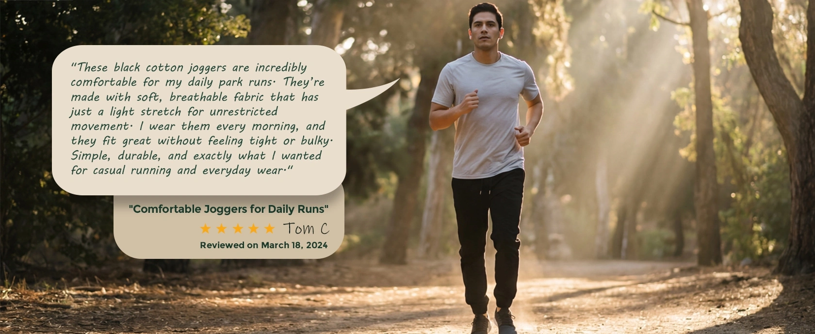 A man jogging on a sunlit wooded trail wearing ItalyMorn black cotton joggers. An overlaid customer review praises the soft, breathable fabric and light stretch that provides unrestricted movement for daily runs.