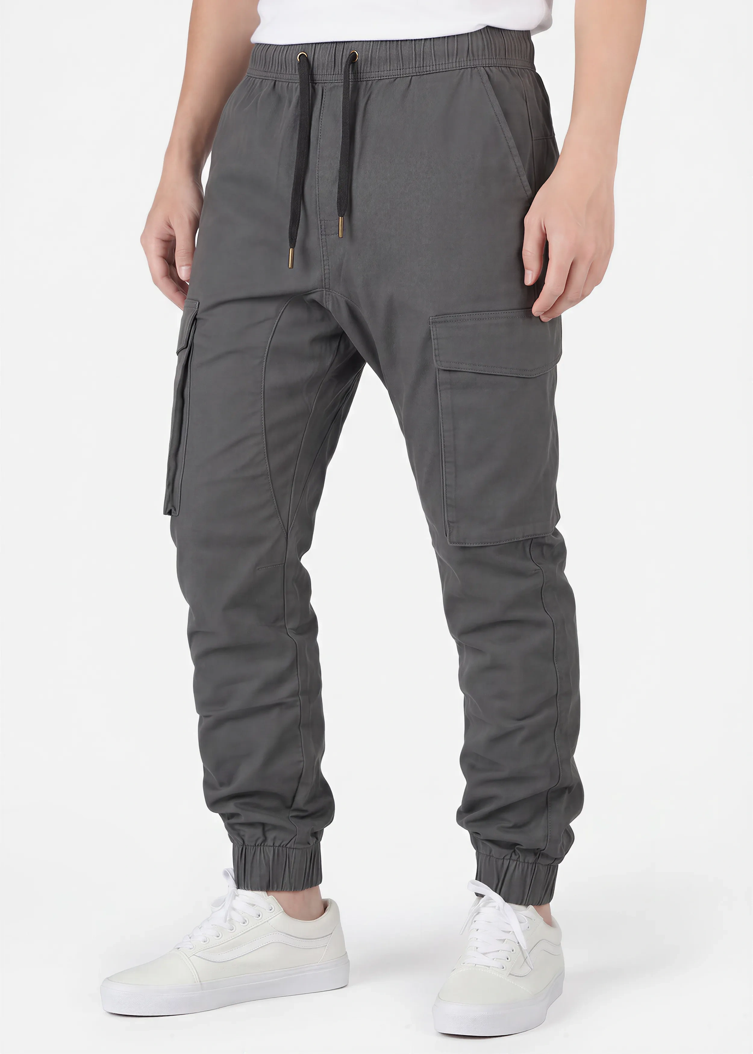 Front view of a male model wearing ITALYMORN men's dark grey cargo joggers, featuring an elastic waistband with black drawstrings, side cargo pockets, and ankle cuffs, paired with a white t-shirt and white sneakers.