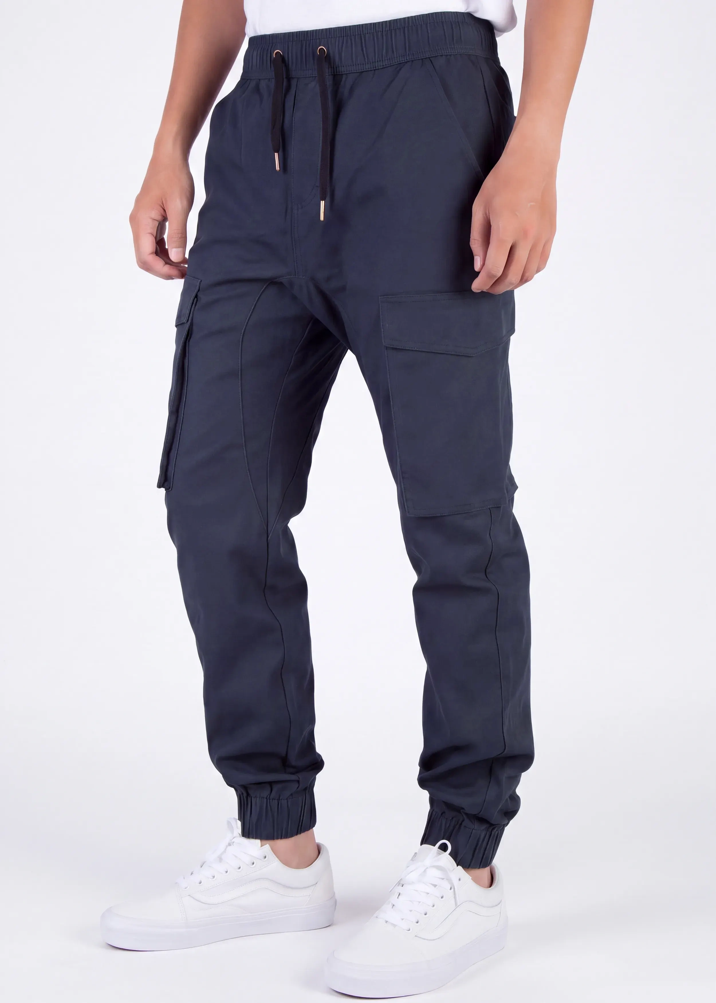 Front view of a male model wearing ITALYMORN men's navy blue cargo joggers, featuring an elastic waistband with drawstrings, side cargo pockets, and ankle cuffs, paired with a white t-shirt and white sneakers.