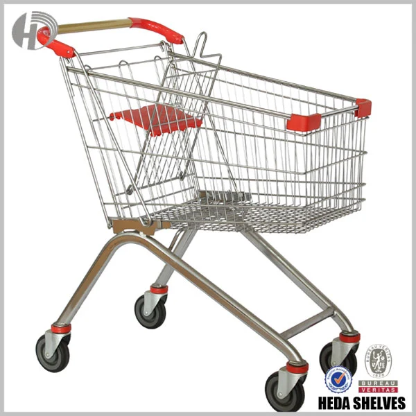 Original HEDA Type B supermarket grocery cart with silver metal wire basket, red push handle, red plastic corner guards, folding child seat and curved tubular four-wheel chassis