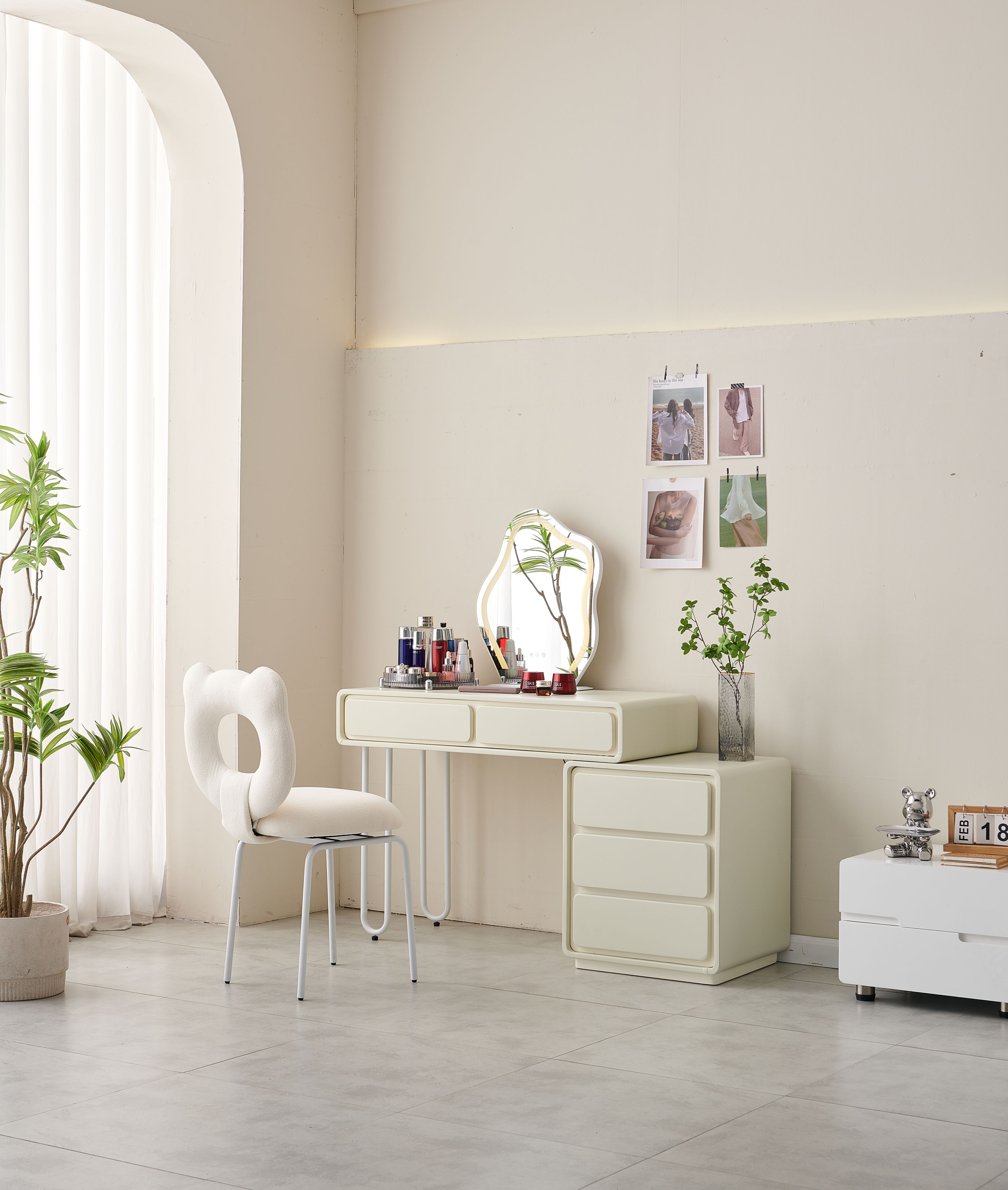 A minimalist bedroom setup with a light-colored desk, a small mirror, and various cosmetics on top.