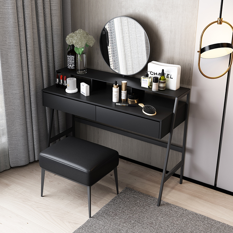 A modern and well-organized bathroom vanity with a black vanity desk, skincare products, hair tools, and a modern pendant light.