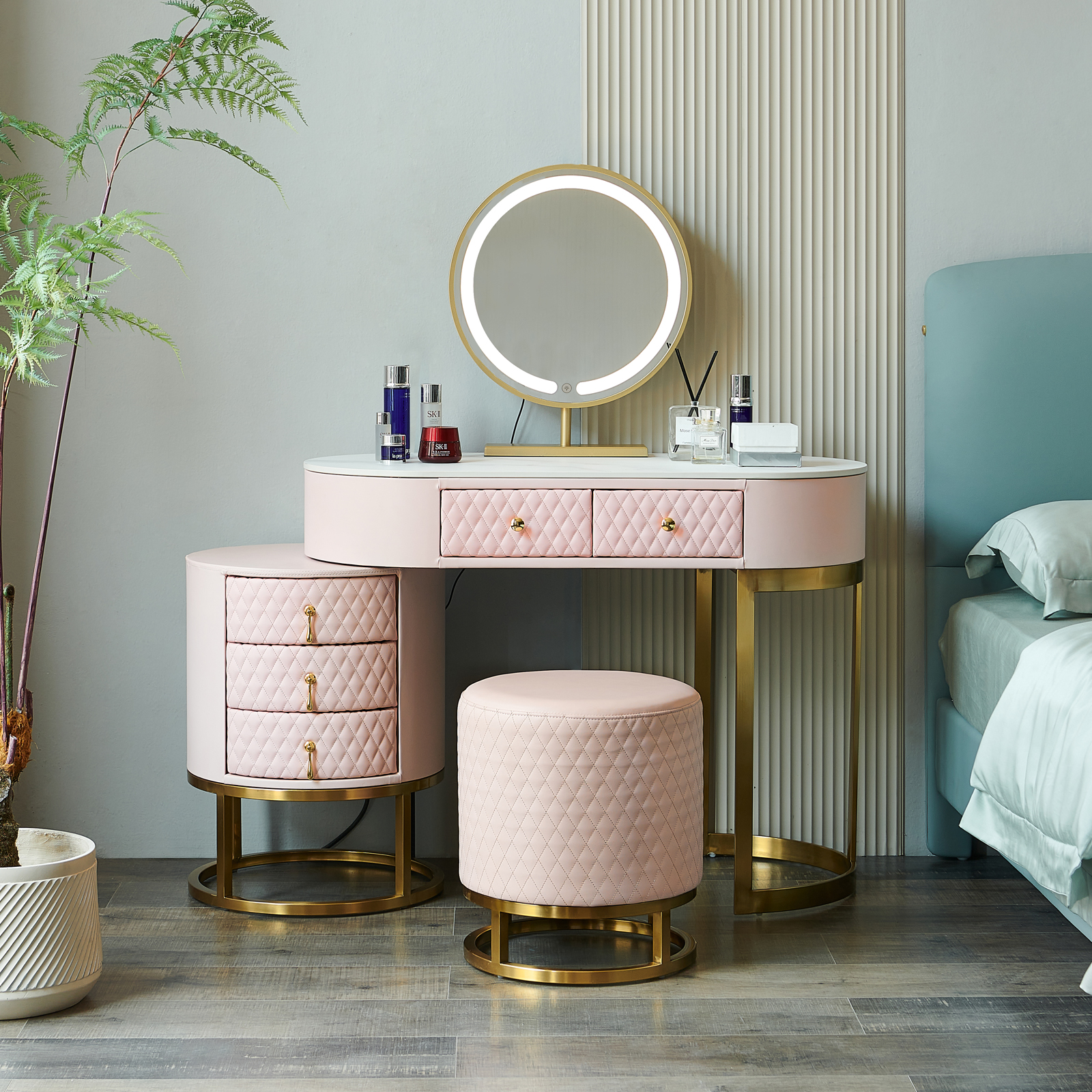 A small vanity or dressing table with a pink color scheme and a round mirror mounted on the wall.