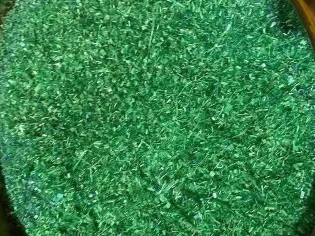 Finely shredded uniform green plastic strap flakes controlled by the bottom sizing screen.