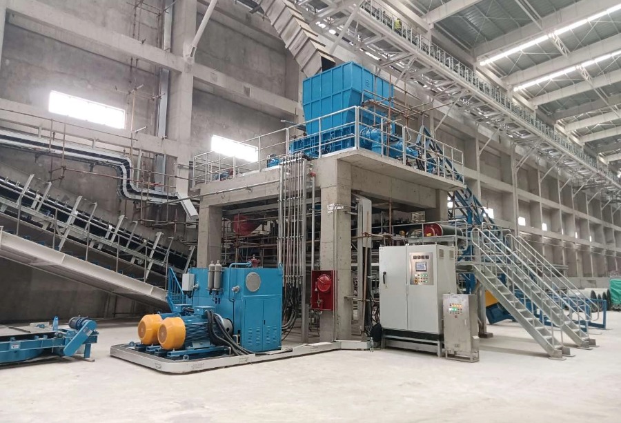 Large industrial paper mill waste shredding recycling system with PLC control panel installed in a modern workshop.