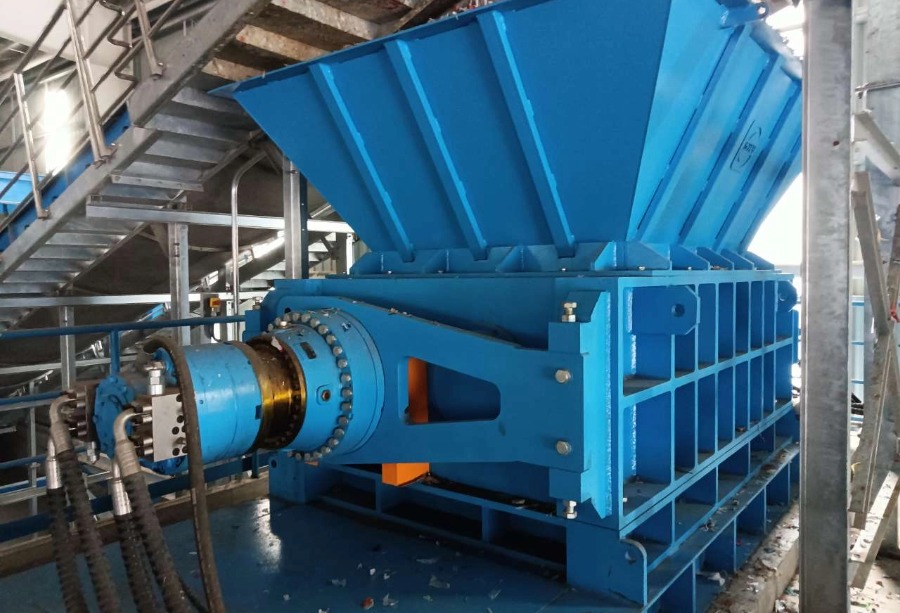 Close up of heavy duty twin shaft ragger tail shredder with a large steel feeding hopper.